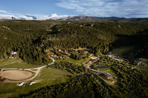 An aerial view of a mountain resort surrounded by a pine forest.