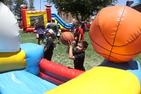 A young boy plays with a basketball near an inflatable play structure outdoors.