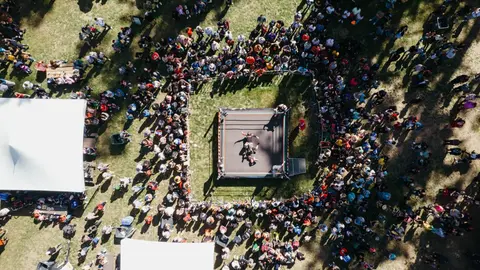 An aerial view of a wrestling ring surrounded by a large crowd of spectators.