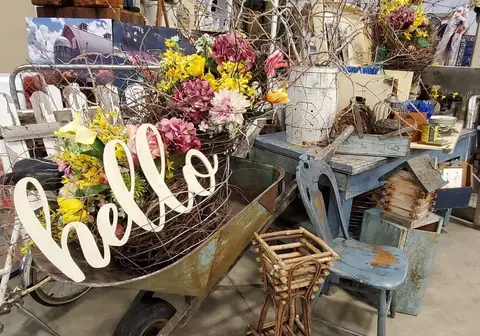 An interior shot shows decorative items including a wheelbarrow with flowers and a sign that says hello.