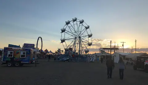 A Ferris wheel at a carnival during sunset.