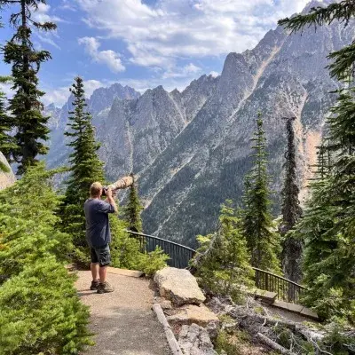 A person takes photos with a long lens from a mountain overlook.