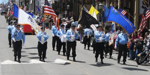 A color photograph of a color guard marching down a street during a parade.