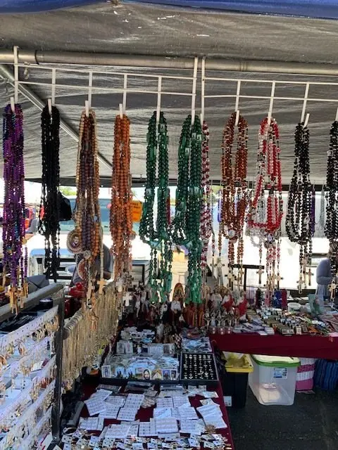 A market stall displays hanging rosaries and religious items.