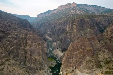 A river flows through a deep canyon with rocky cliffs and tunnels.