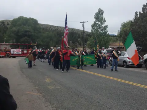 People carrying flags in a parade on a street.