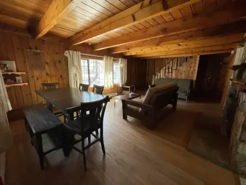 An interior view of a rustic wooden cabin with a dining table and living area.