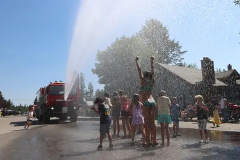 Children play in the water sprayed by a fire truck on a sunny day.