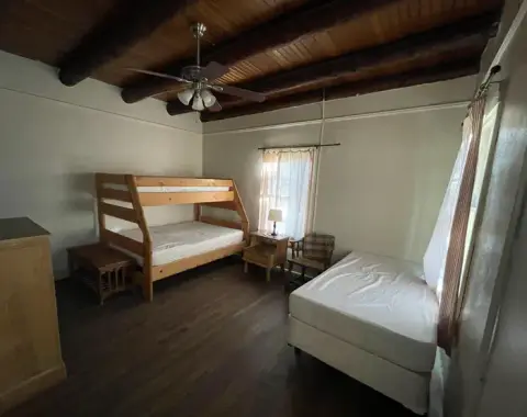 An interior bedroom with wooden bunk beds and a ceiling fan.