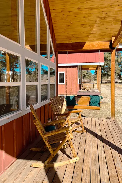 A rustic wooden porch with rocking chairs and a swing.