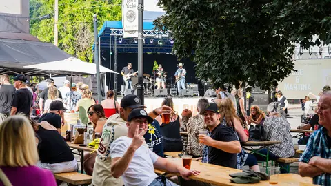 An outdoor concert event with a crowd gathered at picnic tables.