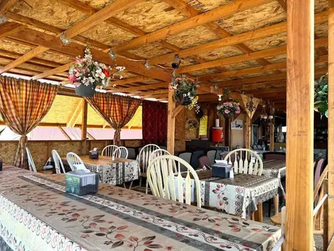 An interior view of a rustic dining area with wooden tables and a wooden ceiling.