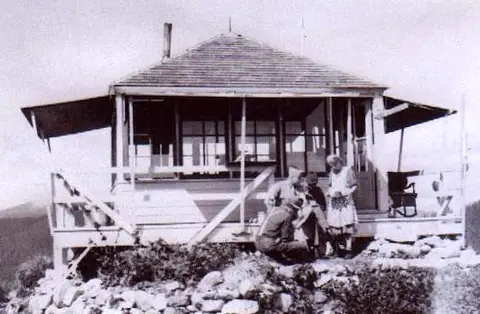 Historic black and white photo of people on the porch of a lookout tower.