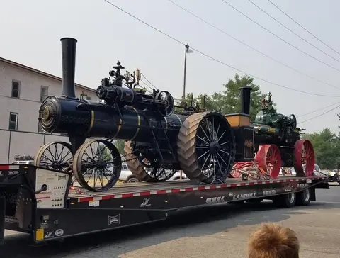 A steam tractor is loaded on a flatbed trailer.