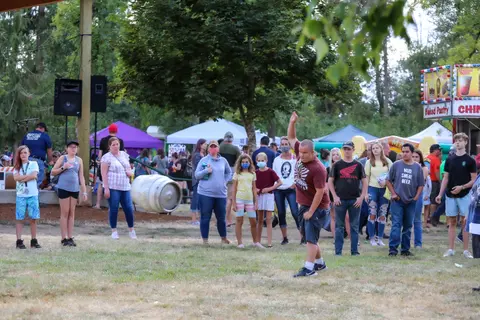 A young person throwing something outdoors with a crowd watching.