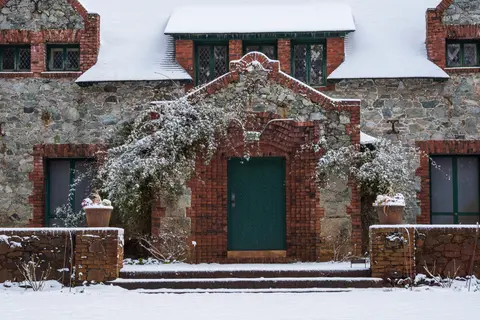 An exterior view of a stone and brick building covered in snow.