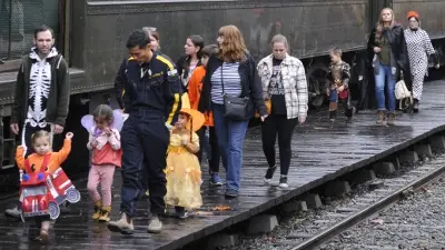 People in costumes walk along a train platform.