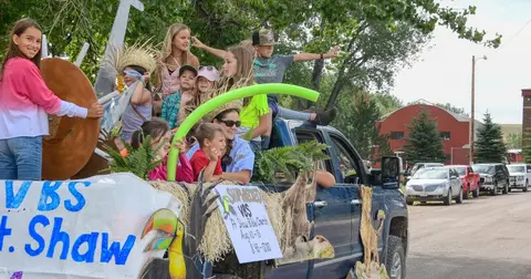 Children ride on a decorated parade float.