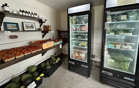 An interior view of a farm store with produce, shelves, and refrigerators.