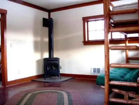 An interior view of a room with a wood stove and log bunk bed.