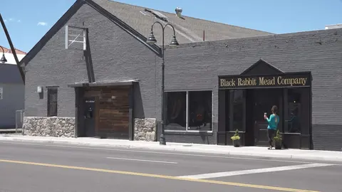 An exterior view of a dark grey brick building with a storefront sign.