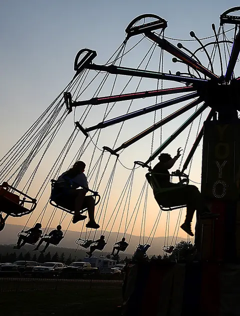 A silhouette of people on a carnival swing ride at sunset.