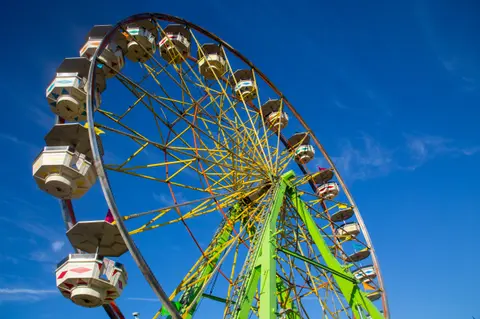 A colorful Ferris wheel stands against a blue sky.