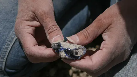 A person's hands holding a blue and white mineral specimen.