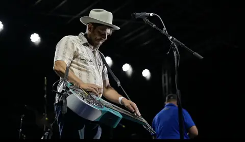 A musician plays a lap steel guitar on stage.