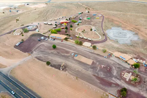 An aerial view shows a roadside attraction and campground in a dry landscape.