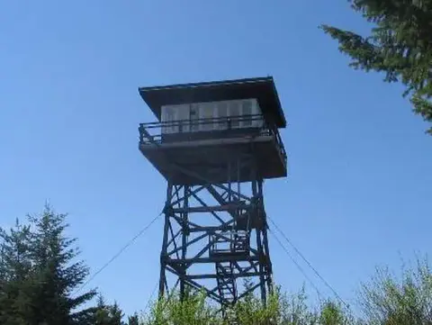 A fire lookout tower stands against a blue sky.