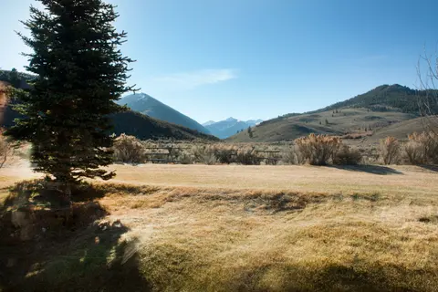 A scenic view of a field and mountains under a blue sky.