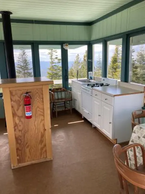 An interior view of a room with a kitchenette and large windows overlooking trees.