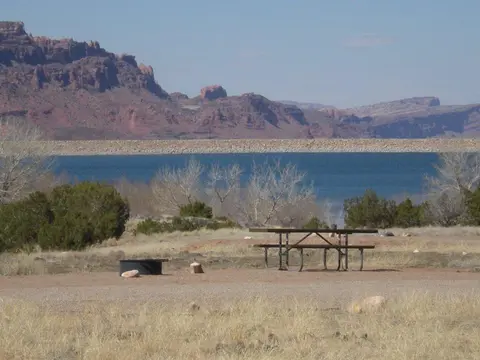A scenic view of a body of water with red rock cliffs in the background.