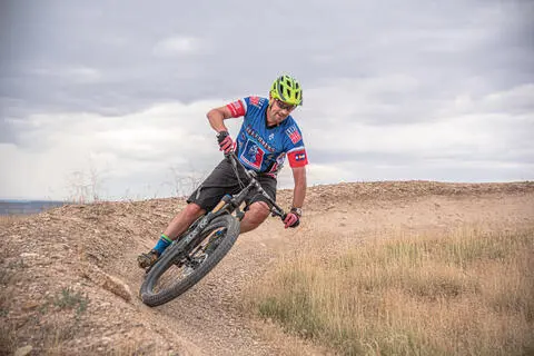 A cyclist rides a mountain bike along a dirt trail.