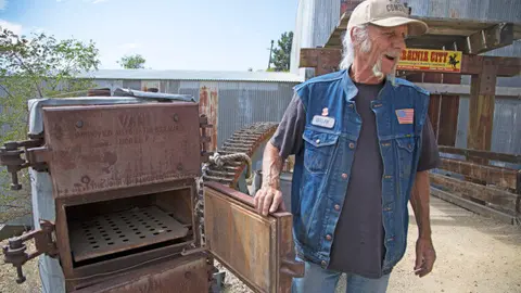 A man stands outdoors next to old industrial equipment.