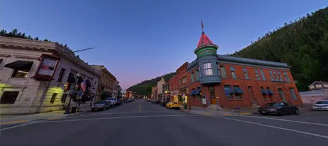 Wide-angle street view of a historic mountain town at dusk.