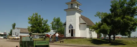 A white historic church stands with people walking near it.