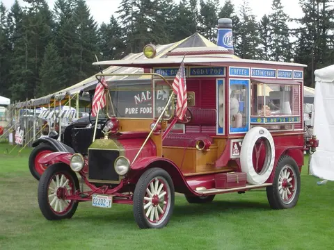 A vintage food truck parked on grass outdoors.