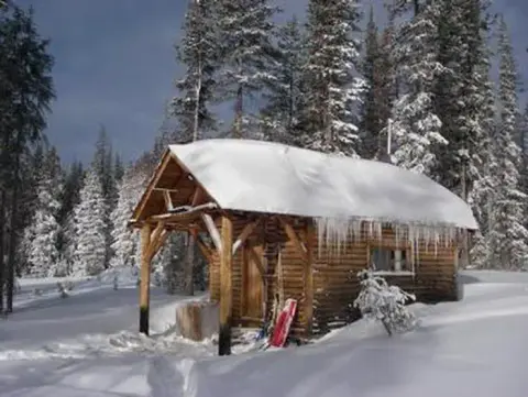 A log cabin covered in snow in a forest.