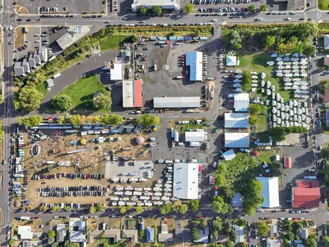 An aerial photograph shows an outdoor fairgrounds with parked cars, RVs, and buildings.