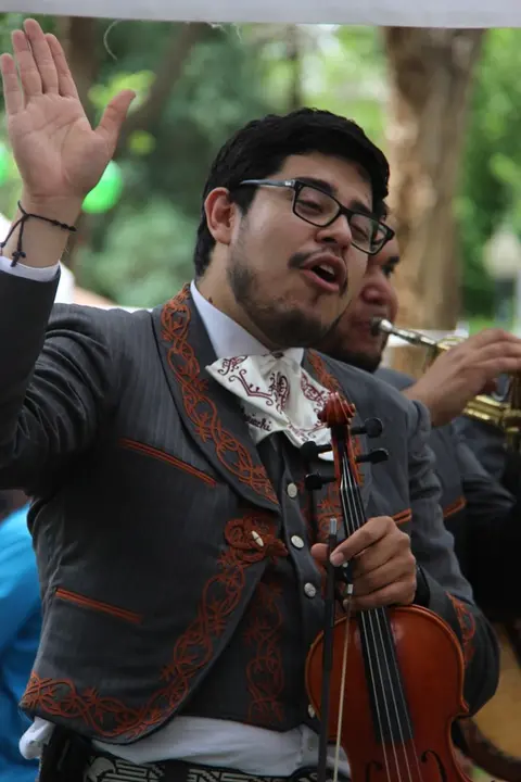 A musician in traditional attire sings while holding a violin.