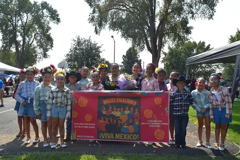 A group of children and adults posing with a banner for a folkloric ballet performance.