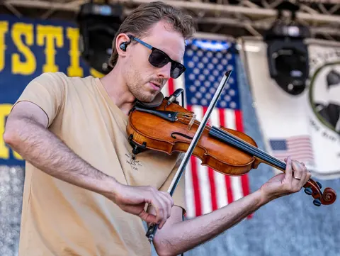 A man plays a violin outdoors.