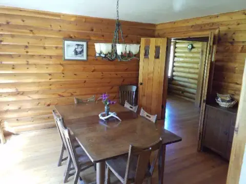 Interior view of a rustic dining room with log walls and a wooden dining table.