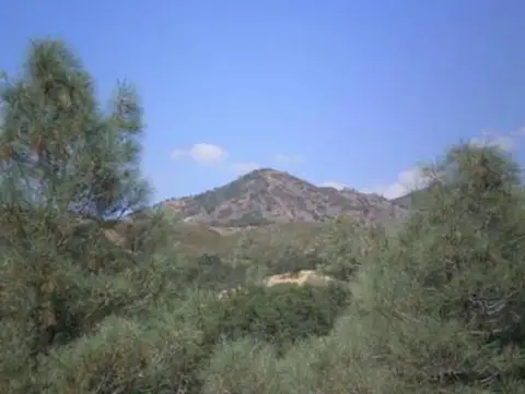 A view of hills and trees under a blue sky.