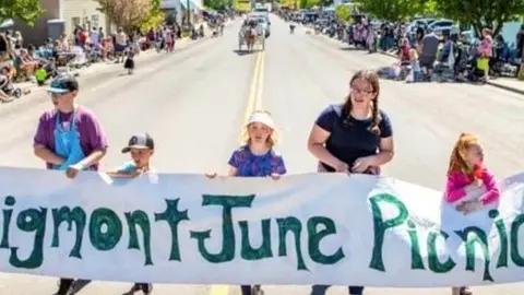 People walking in a parade holding a banner.