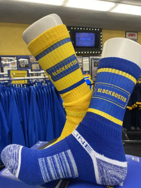 A pair of yellow and blue Blockbuster branded socks on display forms.