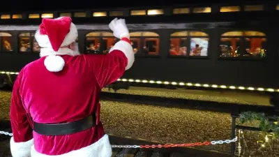 Santa Claus waving to a passing train at night.