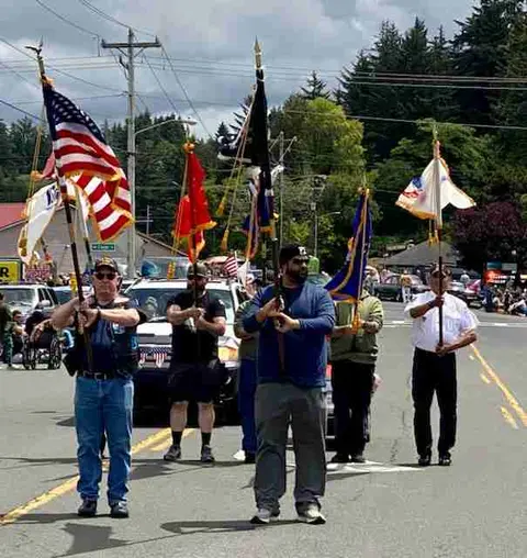 People carrying flags in a parade on a street.